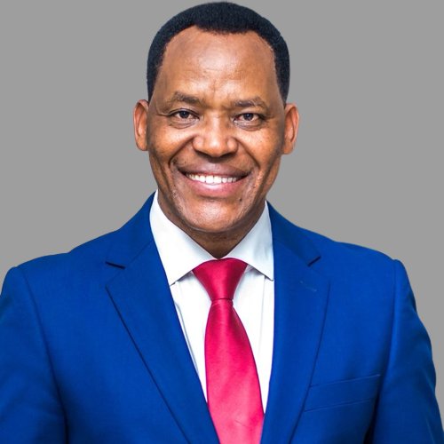 Portrait of Lazaro Nyalandu, smiling, in a blue suit and red tie